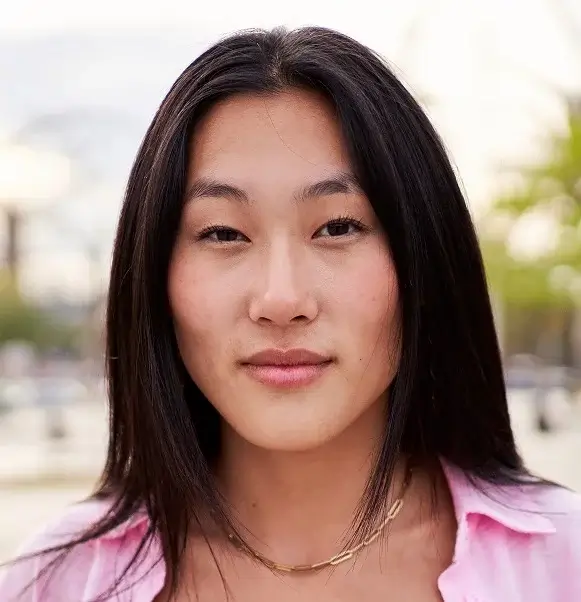 Portrait of Asian woman looking at camera carefree, standing outdoors in a beach city for summer trip.